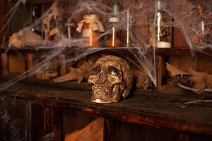 Halloween background Shelves with alchemy tools Skull spiderweb bottle with poison candles photo
