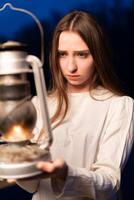 misterioso místico niña en un oscuro noche bosque con un queroseno lámpara en su manos foto
