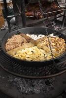 Roasted potatoes cooked outdoors in big metal cauldron pot. Street fast food photo