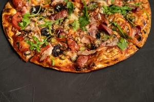 Appetizing pizza with smoked sausages bacon meat tomato cheese arugula photo