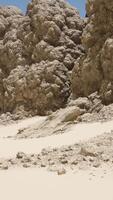 ein sandig Strand mit groß Felsen auf das Seite von es video