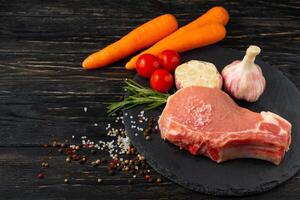 Top view of one pieces raw pork chop steaks with on a black stone cutting board. photo