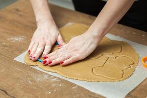 close up of female hands making cookies from fresh dough at home photo