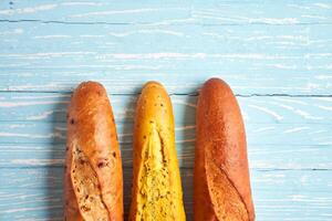 Three crispy french baguettes lie on an old wooden table with free space for text photo