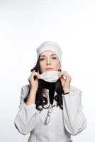 a woman in a white coat is holding a mask photo