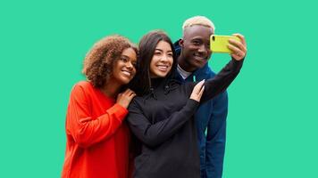 Studio shot of nice young multicultural friends. Beautiful people cheerfully smiling and having fun while making selfie photo. Isolated green background photo