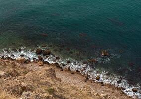 sea wave washes yellow beach of pebbles photo