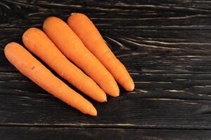 Fresh carrots on cutiing board with black wood background photo