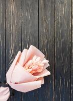 Beautiful bouquet of dry pink flowers on a wooden black background. Minimalism, space for text. Gift Card photo