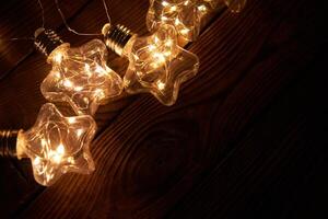 brillante luminoso Navidad guirnaldas en el forma de estrellas mentira en un oscuro de madera antecedentes. foto