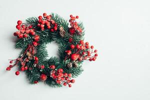 Christmas decorative wreath of holly, ivy, mistletoe, cedar and leyland leaf sprigs with red berries over white background. photo