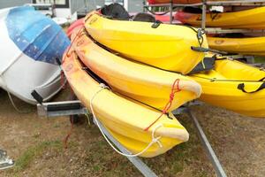 In sunlight, red, yellow and white kayaks placed upside down on metal storage racks. Stocked canoe in the Brest, France 28 May 2018 photo