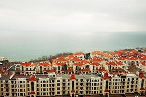 Residential quarter consisting of white houses with orange roofs on the background of the sea. Coast photo