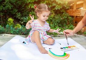 Portrait of little blonde girl painting, summer outdoor. photo