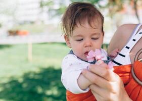 Mother carry a infant baby in wrap sling in park. Springtime. Concept of natural parenting photo