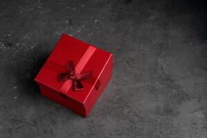 Red square holiday gift box against a dark background photo