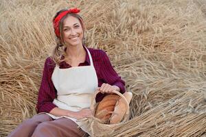 Female farmer sitting wheat agricultural field Woman baker holding wicker basket bread product photo