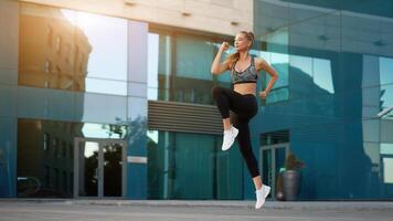 Woman with fit body jumping and running against urban city background photo