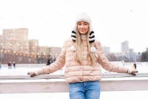 Medium shoot portrait of romantic european lady wears long stylish winter jacket and funny fluffy hat in snowy day. Outdoor photo of inspired blonde woman enjoying winter city.