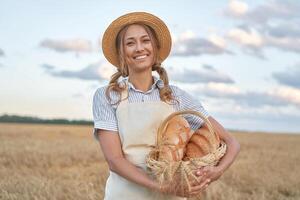 Female farmer standing wheat agricultural field Woman baker holding wicker basket bread product photo