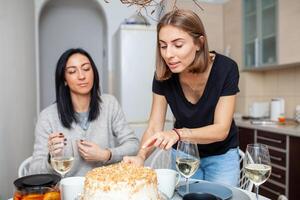 amigos reunión con vino y pastel en el moderno estilo cocina. mujer sonrisa y broma foto