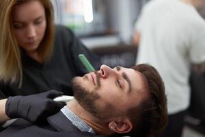 joven hermosa caucásico mujer peluquero cortes barba hermoso hombre a moderno barbería foto