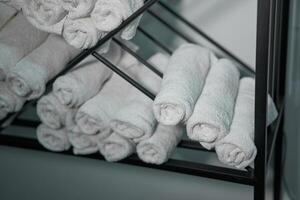 White clean towels rolled up on a roll are stored on shelves in a beauty salon in a barbershop spa. photo