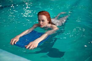 Beautiful young redhead Caucasian girl swims in the indoor swimming pool. Healthy lifestyle. photo