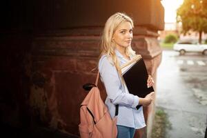 Enthusiastic Happy beautiful young girl smiling and holding pile of books standing near campus lifestyle positivity academic graduating university school photo