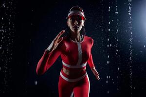 Beautiful young girl in sportswear runing in aqua studio. Drops of water spread about her fitness body. The perfect figure on the background of water splashes. Bad weather for sport photo