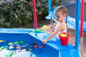 niño pescador atrapando el plastico juguete pescado en piscina diversión parque verano día foto