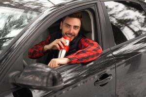 Young attractive Caucasian man sits at the wheel of his car sunny winter day. photo