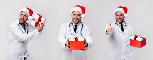 Young handsome doctor in white uniforme and Santa Claus hat standing in studio on white background smile and finger in camera photo