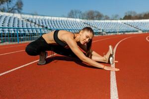 young fitness woman runner warm up before running on track photo