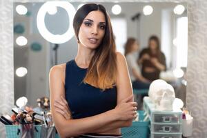 retrato de bonito hembra cosmetólogo en pie posando a lugar de trabajo en pelo y belleza salón foto