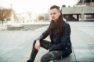 rocker rock star young man walking on the city street autumn day photo