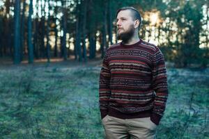 Portrait brutal bearded hipster man in the forest photo