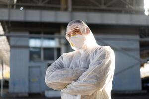 COVID-19 coronavirus doctor standing hospital parking dressed white protective overalls hazmat suit. photo