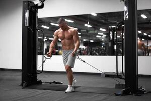 Muscular athletic bodybuilder standing training chest and shoulders muscles on fitness equipment photo