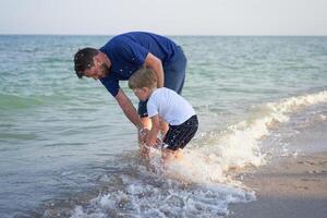 Father son spending time together sea vacation Young dad child little boy walking beach photo