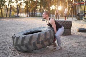 Strong man training workout lifting large tire outdoor DIY gym. photo