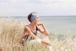 mujer sentado en el antecedentes de el increíble azul mar costa. joven Moda mujer relajarse en el playa. contento isla estilo de vida. azul cielo y cristal mar de tropical playa. foto