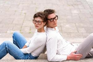 dos atractivo estudiantes hombre y mujer vistiendo elegante lentes sentado piso foto