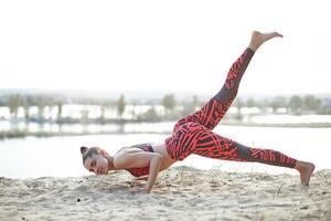 Beautiful Caucasian girl in bright sportswear and leggings makes the bar on the nature. Sports and Healthy lifestyle photo