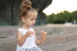 Little caucasian girl 3 years old eats ice cream closeup portrait photo