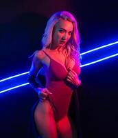 Fashion art photo of elegant model in seductive red swimsuit with light neon colored club spotlights