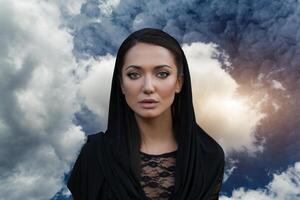 Young beautiful woman with a black hair and in the black dress with the sky backgtound photo