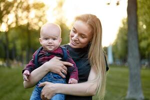 Beautiful young mother walks with her little son in a summer park photo