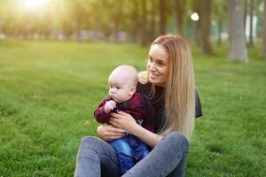 Beautiful young mother walks with her little son in a summer park photo