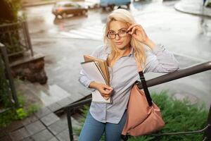 Enthusiastic Serious beautiful young girl holding pile of books standing near campus lifestyle positivity academic graduating university school photo